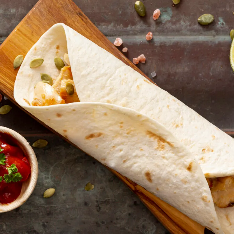 burrito-cutting-board-near-tomato-sauce-sliced-lime-cardamom-seeds-scaled-300x300