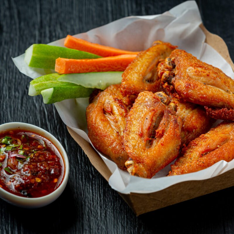 Chicken wings in paper box on a black