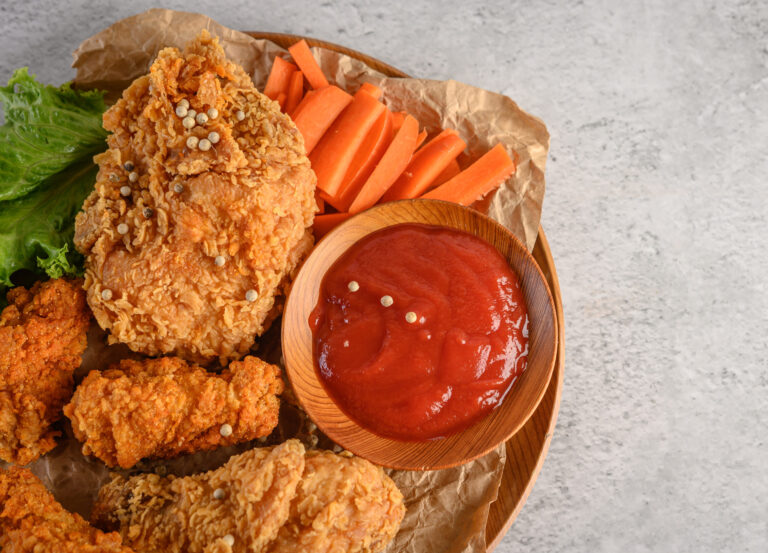 Crispy fried chicken on a wooden plate with tomato sauce and car