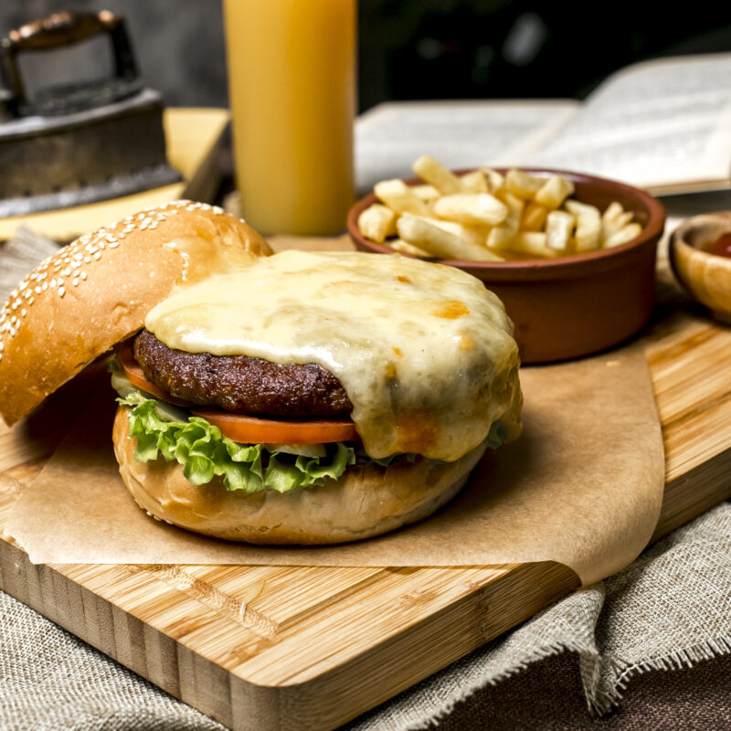 meat burger on wooden board lettuce tomato cheese french fries ketchup side view