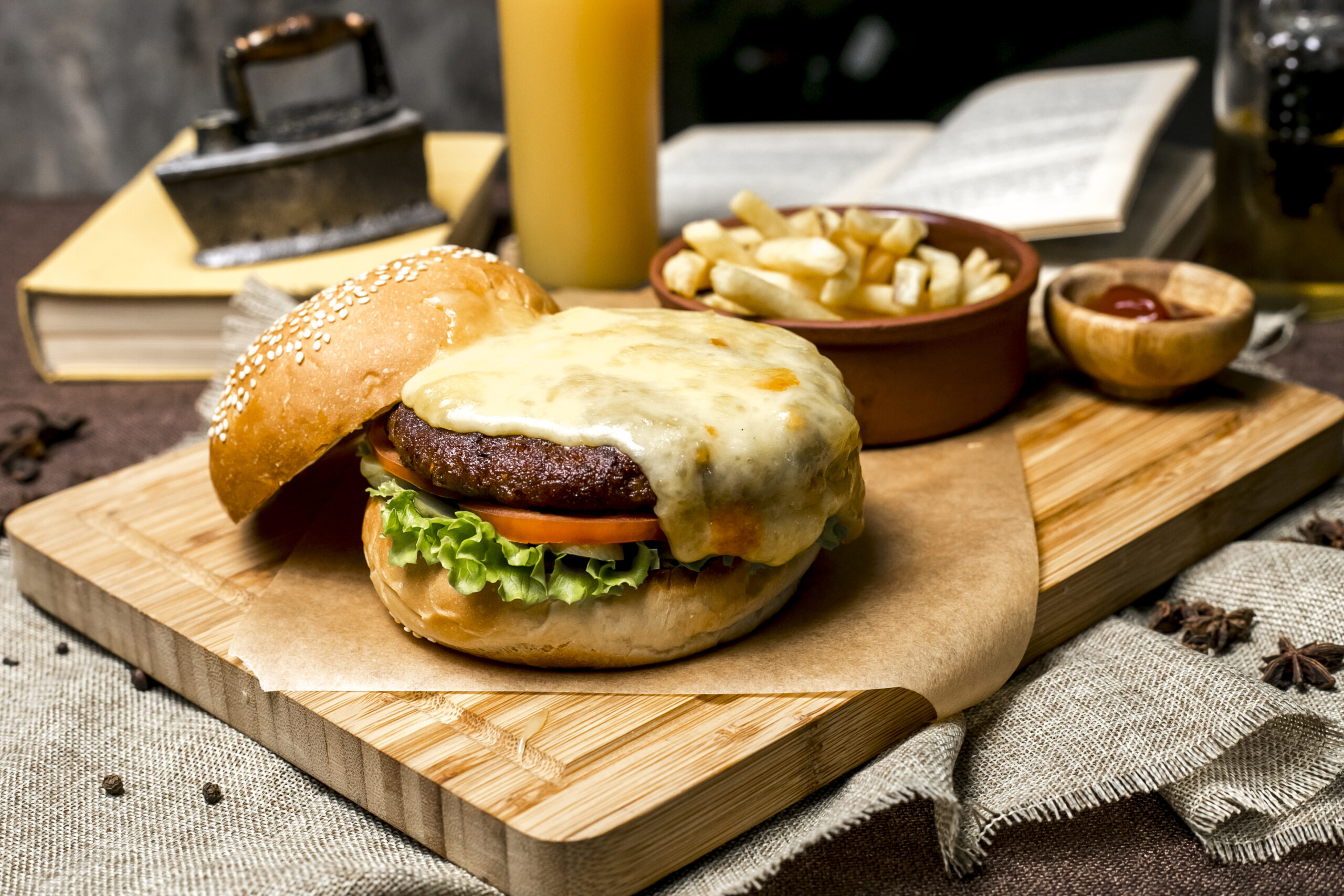 meat burger on wooden board lettuce tomato cheese french fries ketchup side view