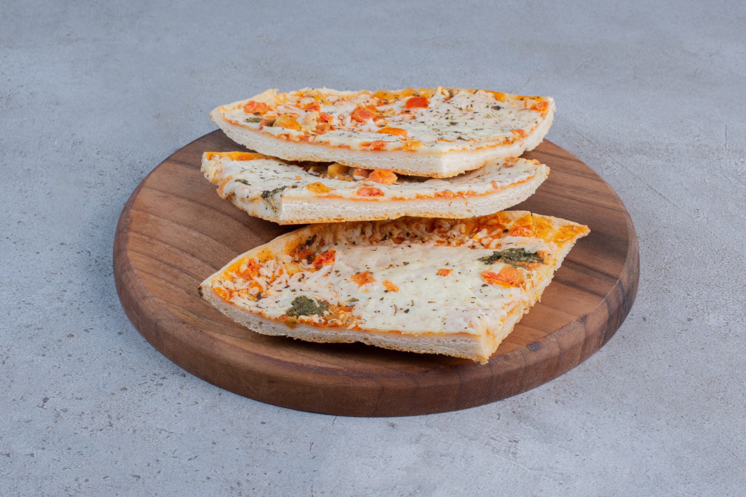 Pizza slices on a wooden board on marble background