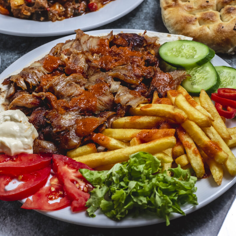 side-view-doner-plate-with-french-fries-tomato-fresh-cucumber-yogurt-bread-table (1)