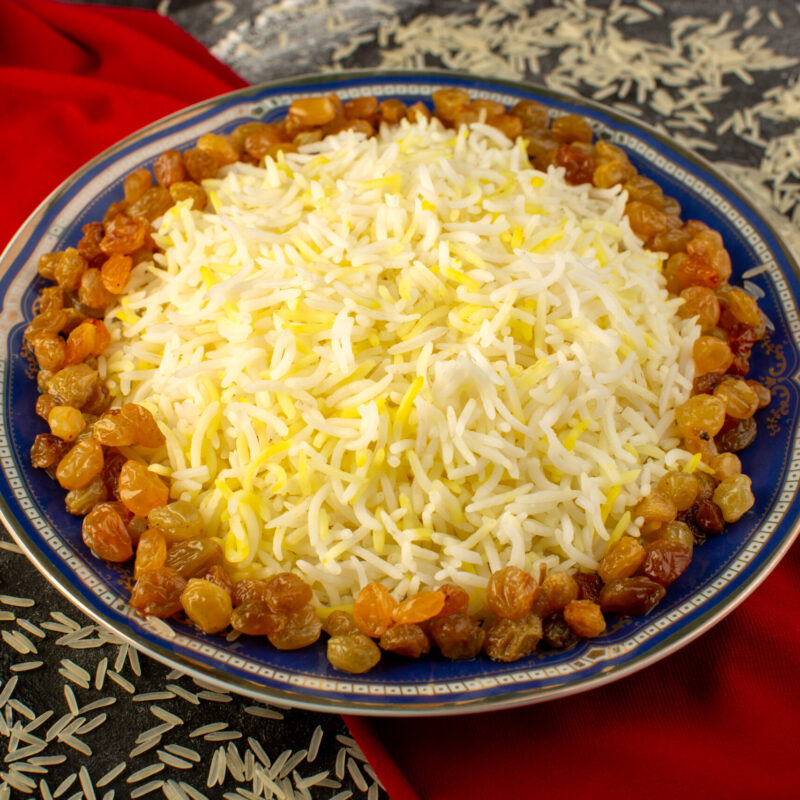 top-view-tasty-pilaf-with-oil-dried-raisins-inside-plate-with-raw-rice-dark-surface