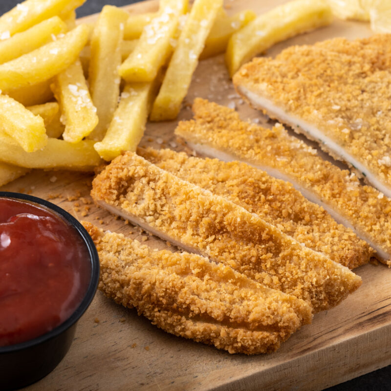Wiener schnitzel with fried potatoes on black background