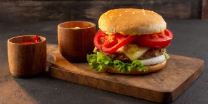 front-view-chicken-burger-with-cheese-green-salad-wooden-desk-sandwich-fast-food-meal
