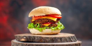 front-view-meat-burger-with-salad-cheese-tomatoes-dark-background