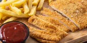 Wiener schnitzel with fried potatoes on black background